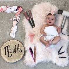 a baby laying on top of a white rug next to hair accessories