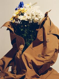 a brown bag with flowers in it sitting on the ground next to a white wall