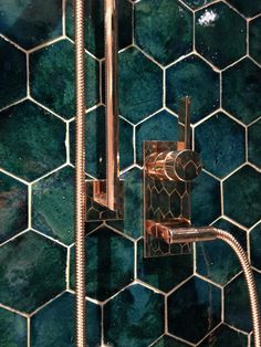 the shower head is attached to the green tiled wall in this bathroom with copper fixtures