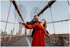 a man and woman standing on a bridge with their arms around each other as they look up at the sky