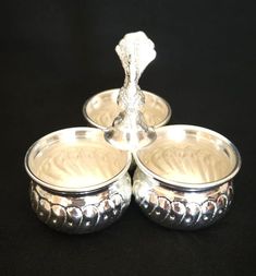 three silver dishes sitting next to each other on a black tableclothed surface,