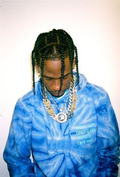 a man with dreadlocks wearing a blue tie - dye hoodie and holding a cell phone