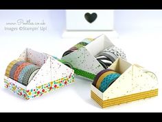 three boxes with different types of washi tapes in them on a white table next to a heart