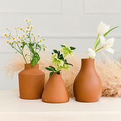 three vases with flowers in them sitting on a table