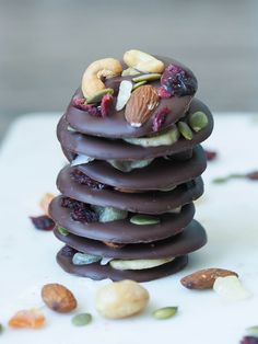 a stack of chocolate covered cookies with nuts and dried fruit on top, in front of the words dark chocolate snack bites