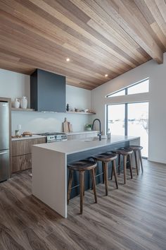 a kitchen with an island and stools in front of the counter top that is made of wood