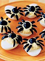 deviled eggs with black and white decorations on an orange tray, ready to be eaten