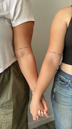 two people holding hands with tattoos on their arms