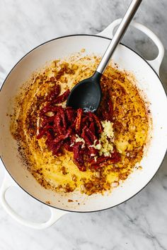 a pot filled with food and a spoon in it on top of a marble counter