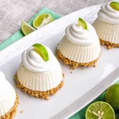 four desserts on a white plate with limes around them and one is topped with whipped cream