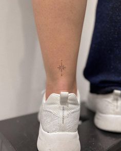 a woman's foot with a small cross tattoo on her left side calfocks