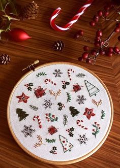 a cross stitch christmas pattern on a wooden table next to candy canes and decorations