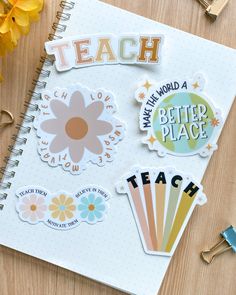 an open notebook with stickers on it next to some flowers and pencils in the background