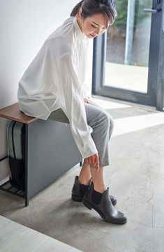 a woman sitting on top of a wooden bench