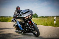 a man riding on the back of a black motorcycle down a curvy road