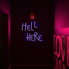 there is a neon sign in the corner of this room that says hello here