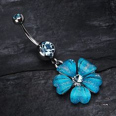 a blue flower belly ring with clear crystal stones on it's end and an attached navel bar