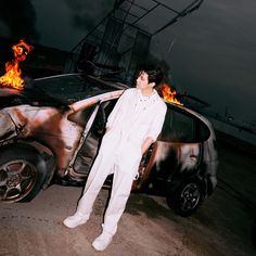 a man standing in front of a car with flames coming out of the back door