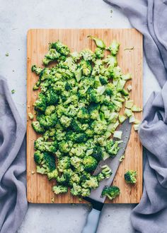 broccoli florets on a cutting board next to a knife and napkin