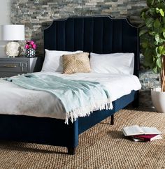 a bed with a blue headboard and pillows on top of it next to a lamp