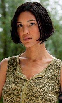 a woman standing in front of trees with her hand on her hip and looking at the camera