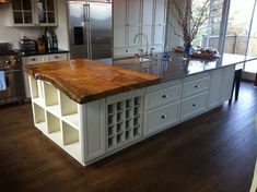 a kitchen with an island made out of wood and white cabinets in the middle of it