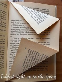 an open book with folded pages on top of it and the words folded right up to the spine