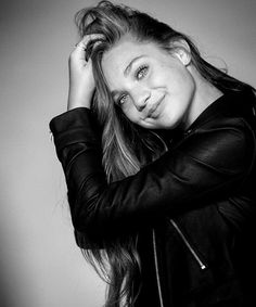 a black and white photo of a woman with her hair blowing in the wind, wearing a leather jacket