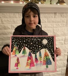 a young boy holding up an art project