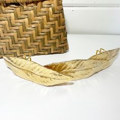 a woven basket next to a wooden boat on a white surface with a brown bag in the background