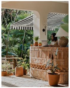 a woman sitting at a table with a laptop on her lap in front of some potted plants