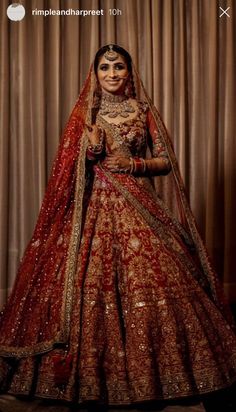 a woman in a red and gold bridal gown posing for the camera with her hands on her hips