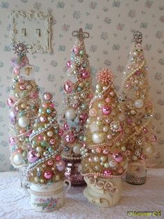 three small christmas trees are sitting next to each other on a table in front of a wall