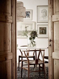 a vase with flowers sitting on top of a table next to a chair and door