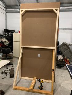 a large wooden frame sitting on top of a table in a room filled with tools