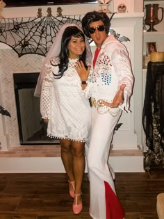 two people dressed up as elvis and bride in front of a fireplace with spider webs on the mantel