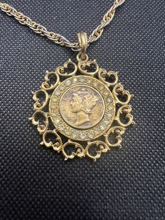 Vintage, pre-owned Liberty Dime pendant necklace. See photos for condition. Hallmarked Pendant Costume Necklace, Costume Jewelry Pendant Necklace, Victorian Jewelry With Coin Pendant, Ornate Coin Pendant Jewelry, Vintage Gold Jewelry With Coin Pendant, Victorian Pendant Necklace For Anniversary, Retro Medallion Necklace With Vintage Charm, Antique Gold Coin Pendant Jewelry For Collectibles, Victorian Pendant Necklace For Vintage Events