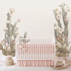 a baby crib next to a cactus wall mural