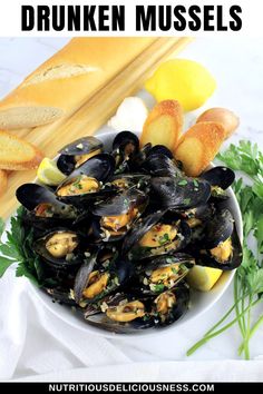 mussels in a white bowl with bread and parsley on the side