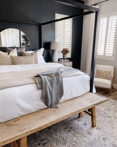 a bed with white sheets and pillows on top of it next to a wooden bench