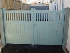 a blue gate is open in front of a white wall and fenced yard area