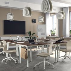 a room that has some chairs around a table with a laptop on it and lights hanging from the ceiling