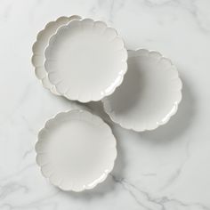 three white plates sitting on top of a marble counter