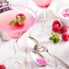 two glasses filled with raspberry martini on top of a table