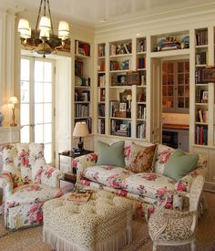 a living room filled with lots of furniture and bookshelves covered in floral fabrics