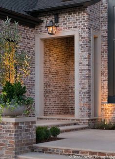 a brick house with steps leading up to the front door and light on it's side