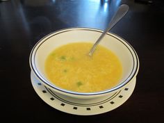 a bowl of soup with a spoon in it sitting on a table next to a plate