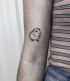 a small hamster tattoo on the left inner forearm and arm, with a black outline