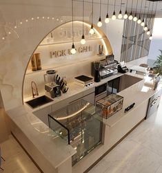 an open kitchen with lots of counter space and lights hanging from the ceiling above it