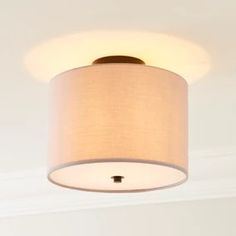 a white ceiling light with a beige shade on the bottom and a brown trim around it